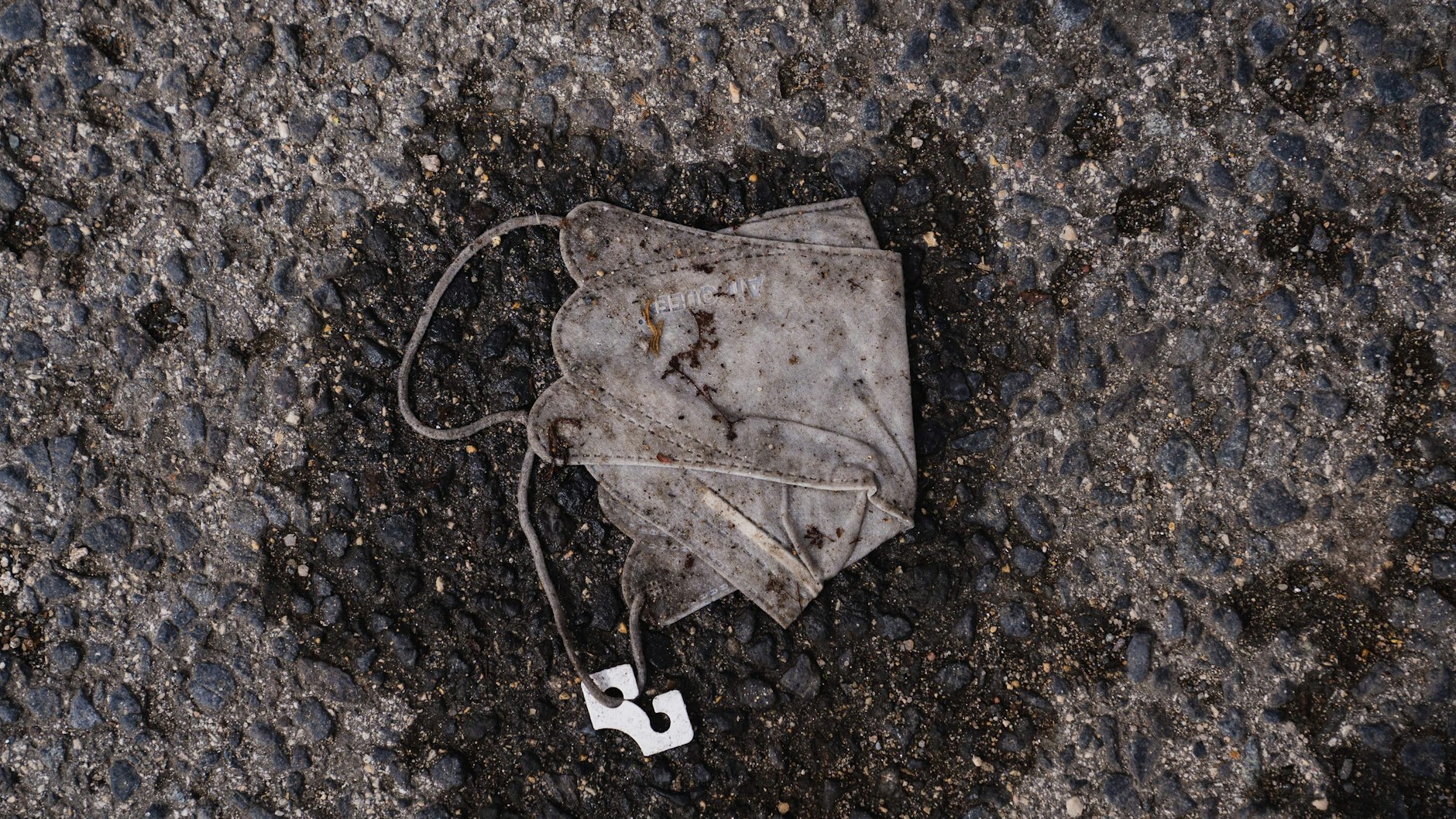 Eine verdreckte und platt getretene FFP2 Maske liegt auf einer Straße (Symbolbild).