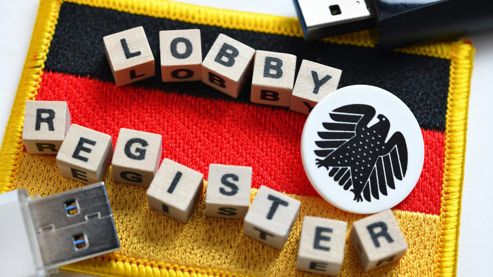 Buchstabenwürfel formen das Wort „Lobbyregister“ auf einer Deutschlandfahne mit Bundesadler (Symbolbild). 