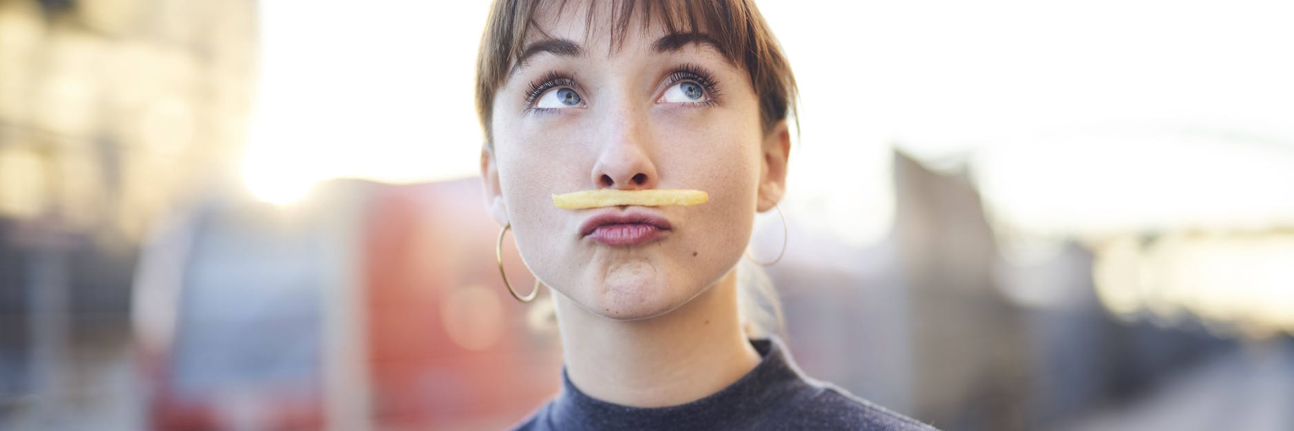 Eine Frau taxiert eine Pommes auf ihrer Oberlippe.