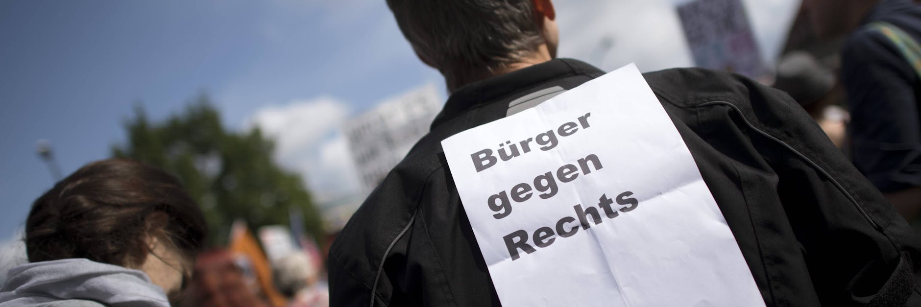 Ein Mann trägt einen Zettel mit Bürger gegen Rechts auf dem Rücken.