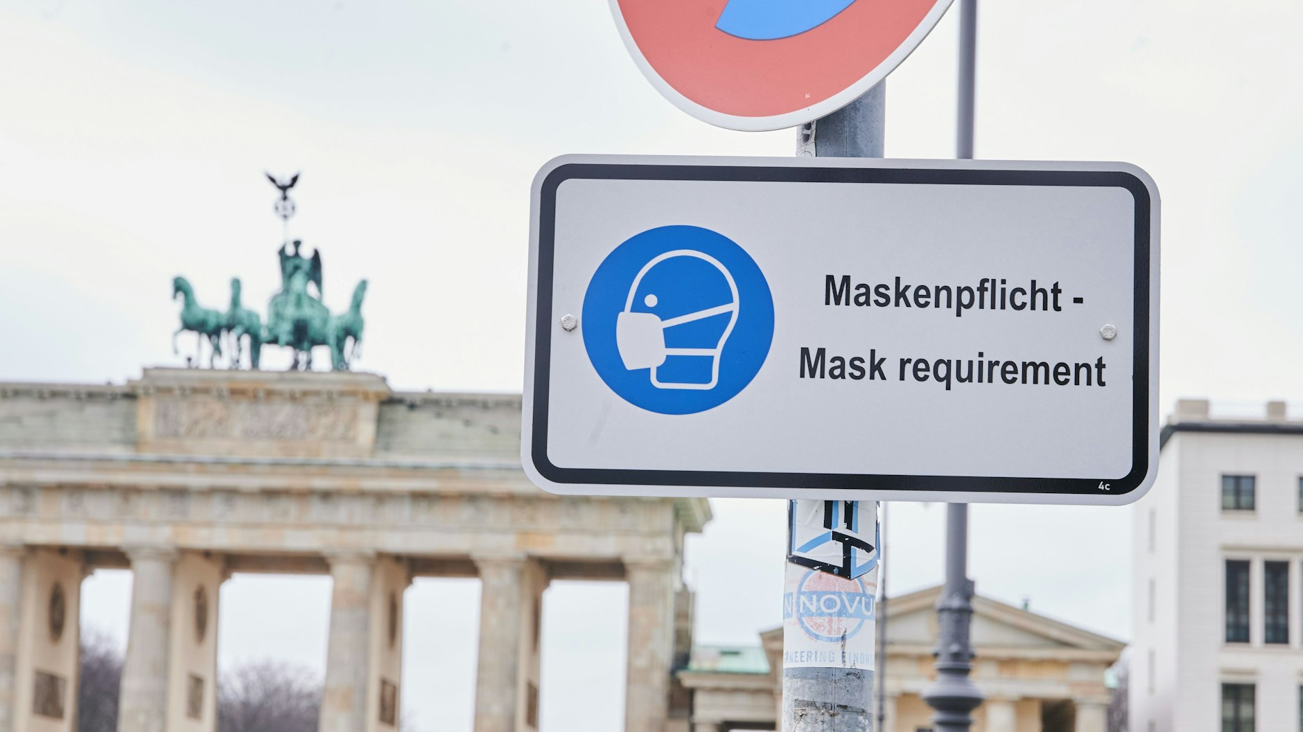 Ein Schild weist am Brandenburger Tor auf die Maskenpflicht hin (Symbolbild).
