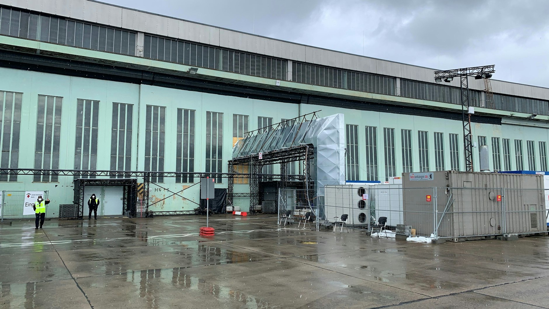 Vor dem Impf-Hangar in Tempelhof wurden große Heiz- und Belüftungsanlagen aufgestellt. Der schwarze Streifen über den Rolltoren ist der Taubenschutz.