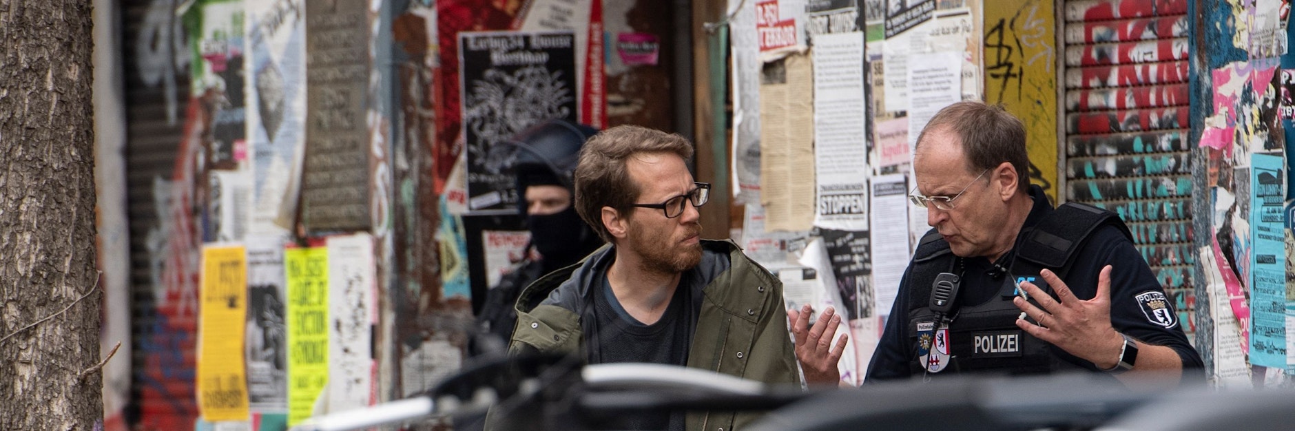 Baustadtrat Florian Schmidt (l.) steht 2020 mit einem Polizeibeamten in der Rigaer Straße, als Beamte auf richterliche Anordnung Wohnungen durchsuchten. 