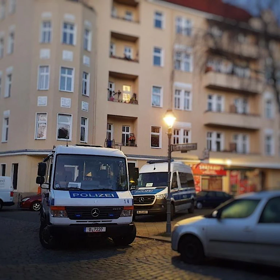 Mannschaftswagen der Berliner Polizei stehen vor einem Wohnhaus, das durchsucht wird.&nbsp;
