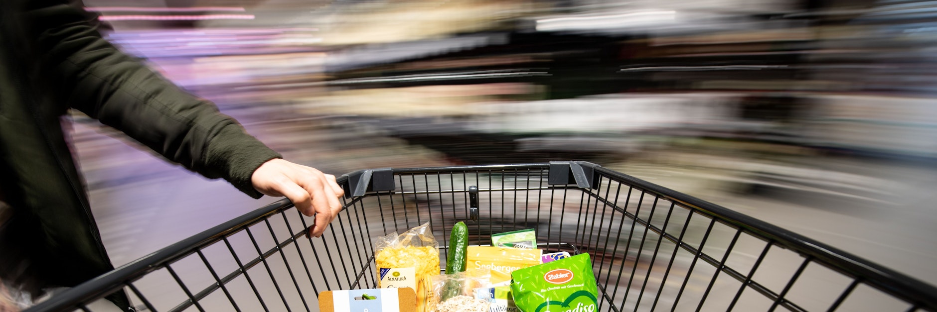 Ein Einkaufswagen wird durch einen Supermarkt geschoben.