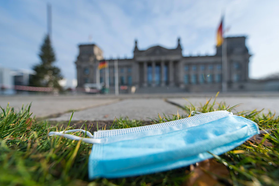 Eine Einwegmaske liegt auf der Wiese vor dem Reichstagsgebäude in Berlin.&nbsp;