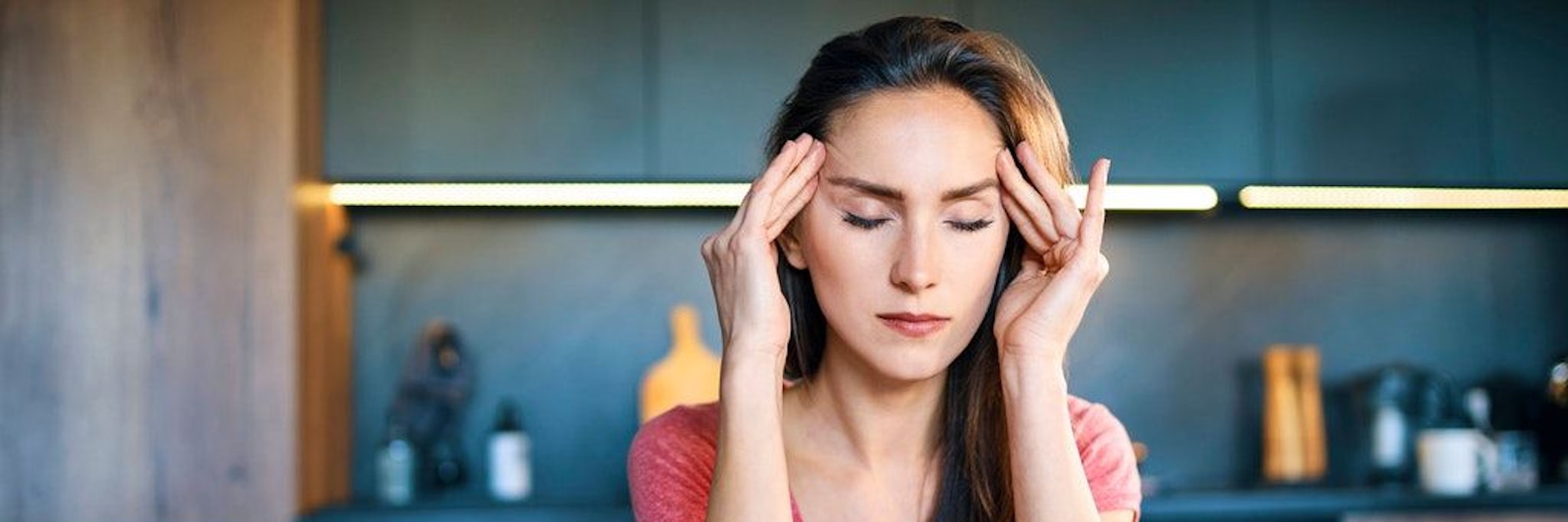 Junge Frau mit Kopfschmerzen im Homeoffice (Symbolbild).