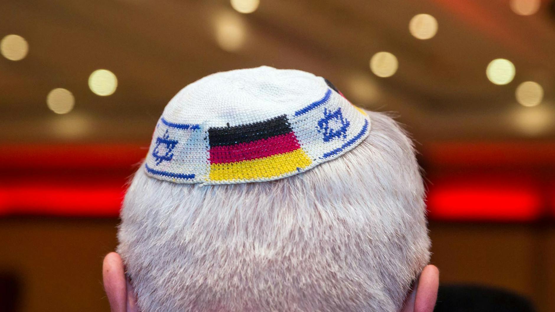 Ein Mann trägt eine Kippa mit eingearbeiteten israelischen und deutschen Fahnen