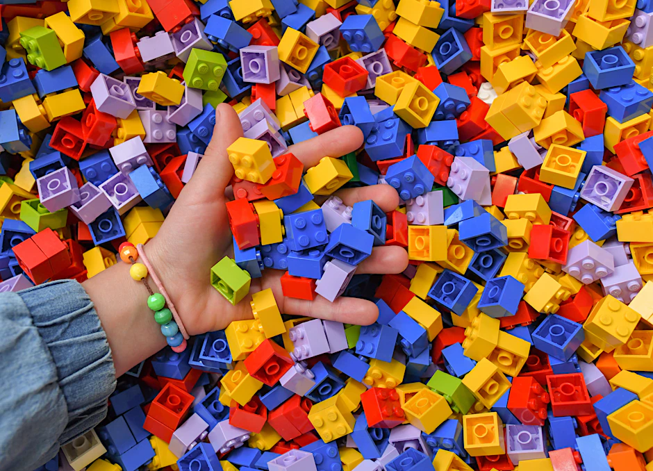 Ein Mädchen greift in eine Kiste voller Lego-Steine. Viele verbinden mit Lego eine kreative, bunte Spielwelt für Kinder und Jugendliche.&nbsp;