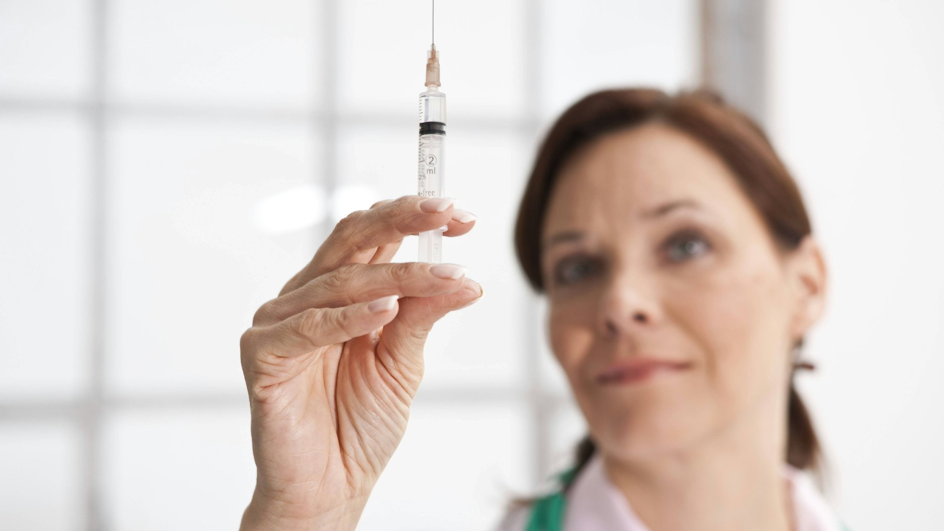 Ärztin hält prüfend eine Spritze in der Hand.