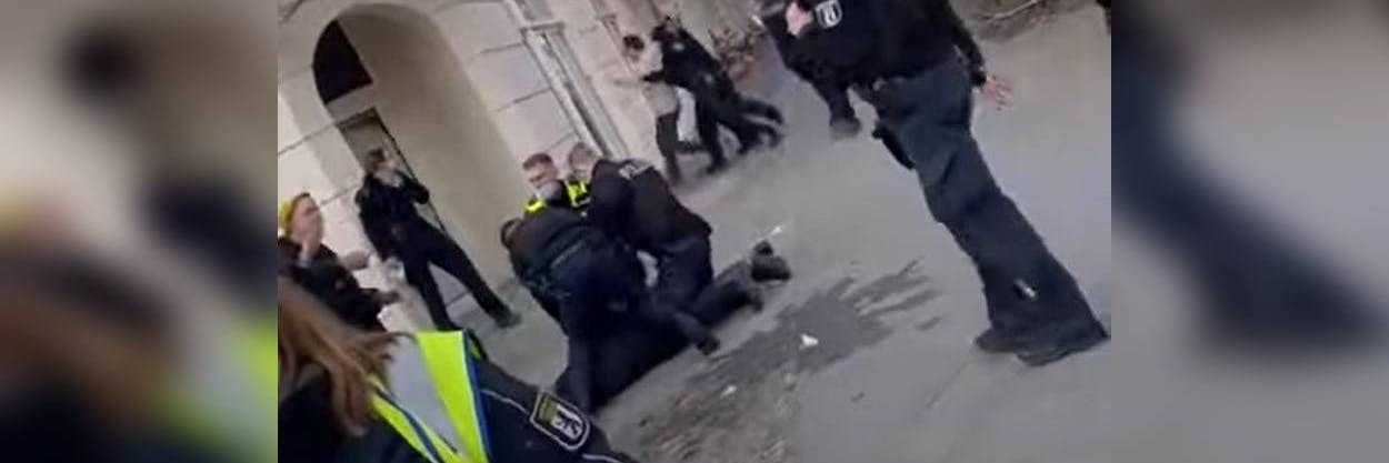 Ein Mann wird zu Boden gedrückt, im Hintergrund wird Hans-Conrad Walter von Polizisten angegangen.