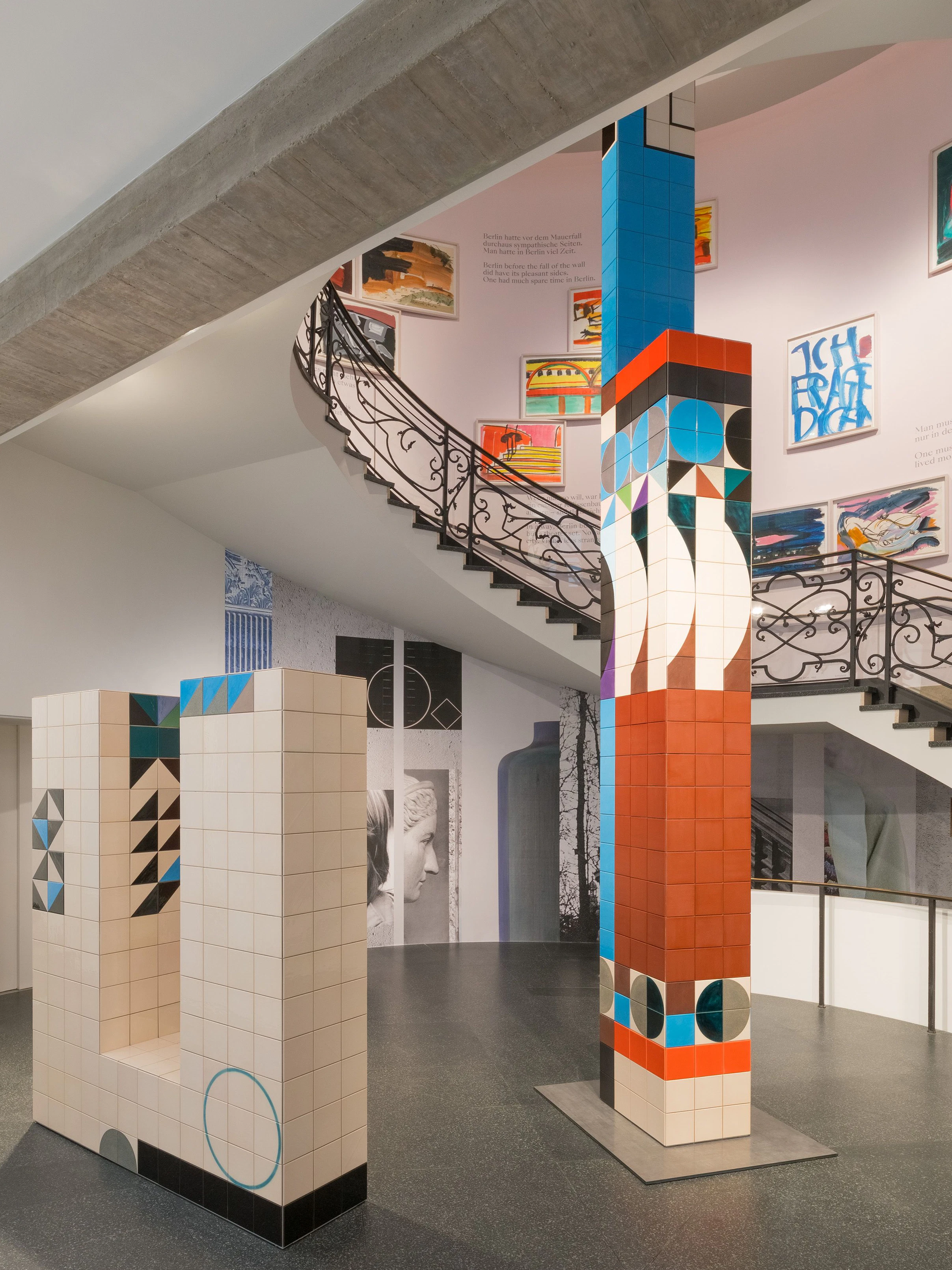 Blick ins Foyer mit Treppenhaus: Claudia Wiesers Rauminstallation „In the Round“ aus gefliesten Säulen mit abstrakten Mustern