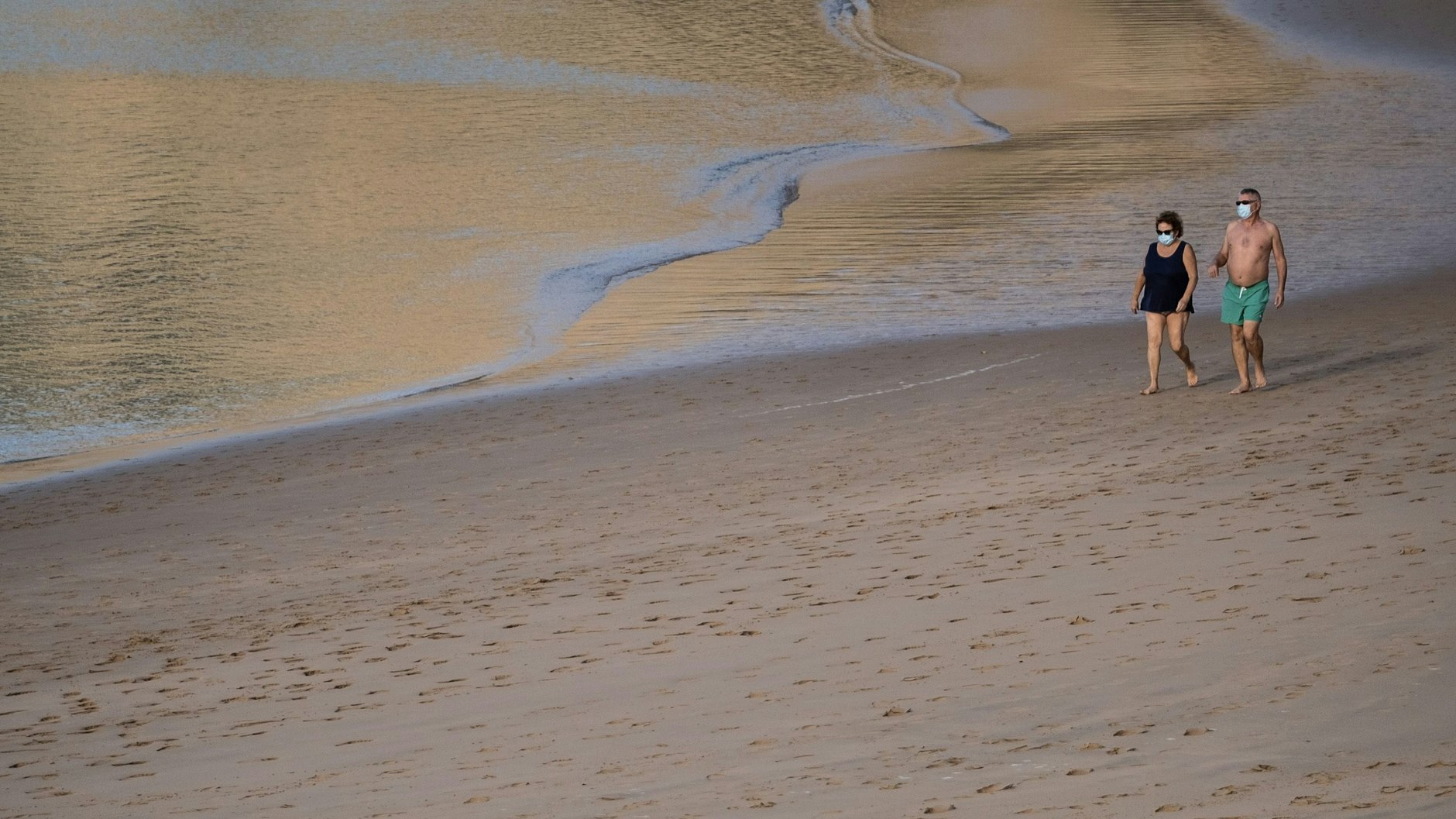 Ein Paar mit Maske spaziert am Strand Las Teresitas.