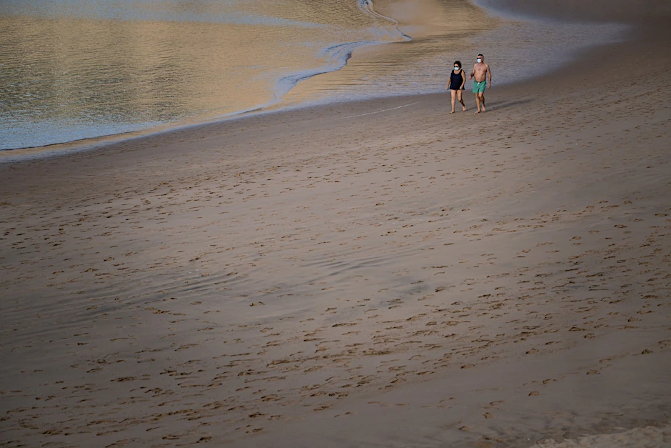 Ein Paar mit Maske spaziert am Strand Las Teresitas.