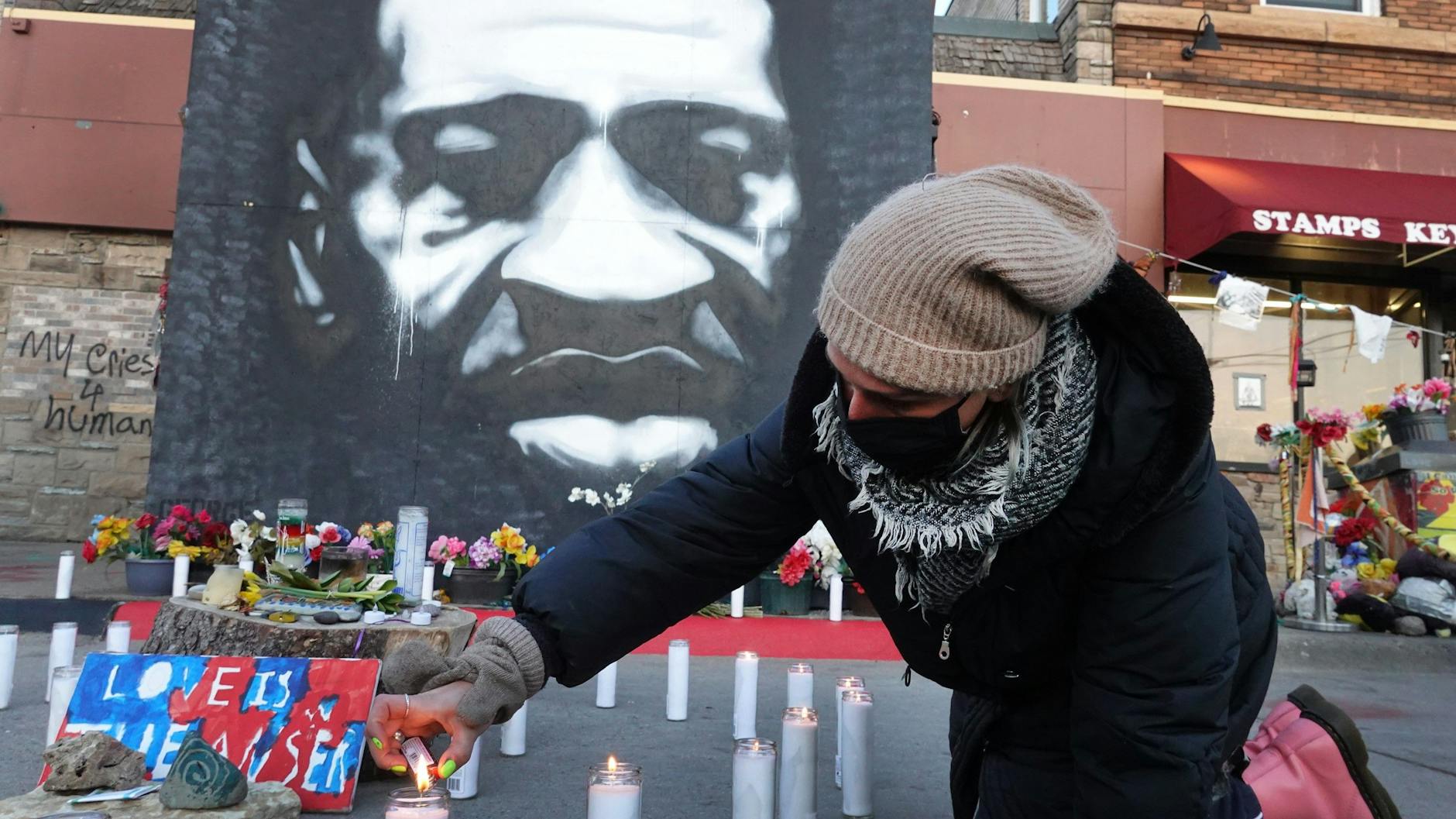 Vor einem Porträt von George Floyd zündet ein Anwohner in Minneapolis Kerzen im Gedenken an den Afroamerikaner an.