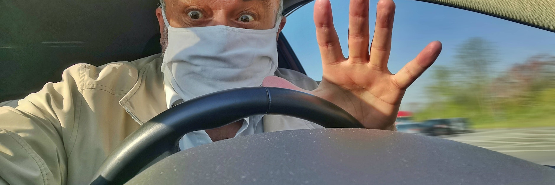Ein Mann mit Mund-Nasen-Schutz am Steuer (Symbolfoto).