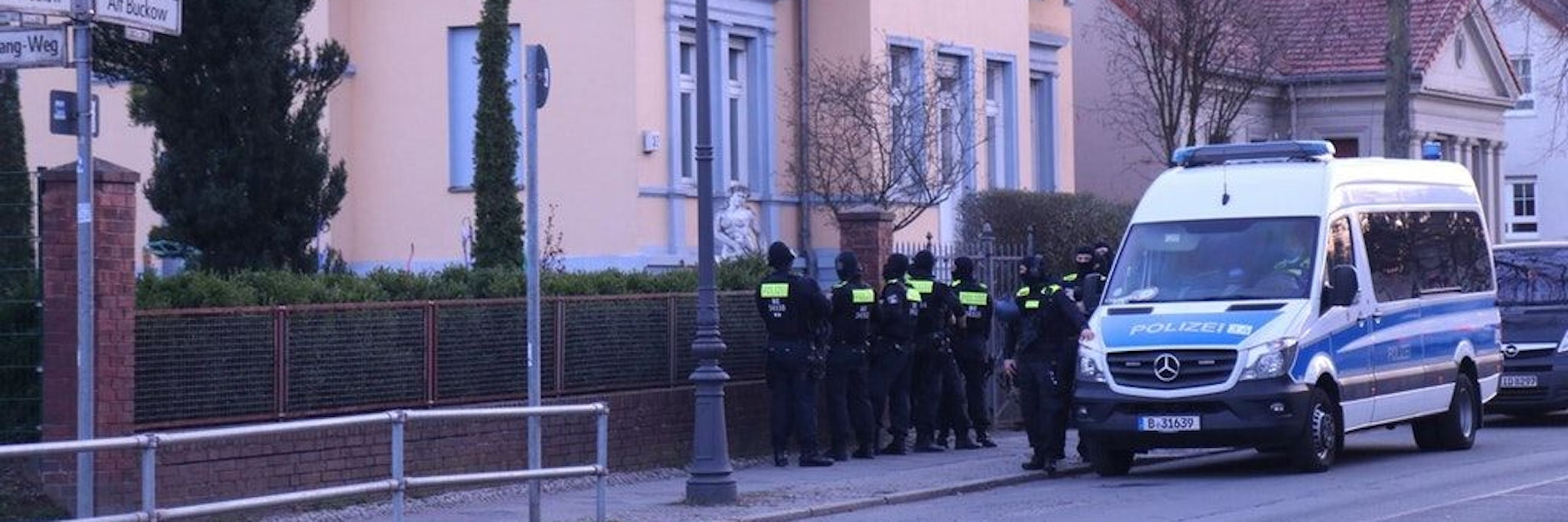 Einsatzkräfte der Polizei stehen am Dienstagabend in der Straße Alt-Buckow.
