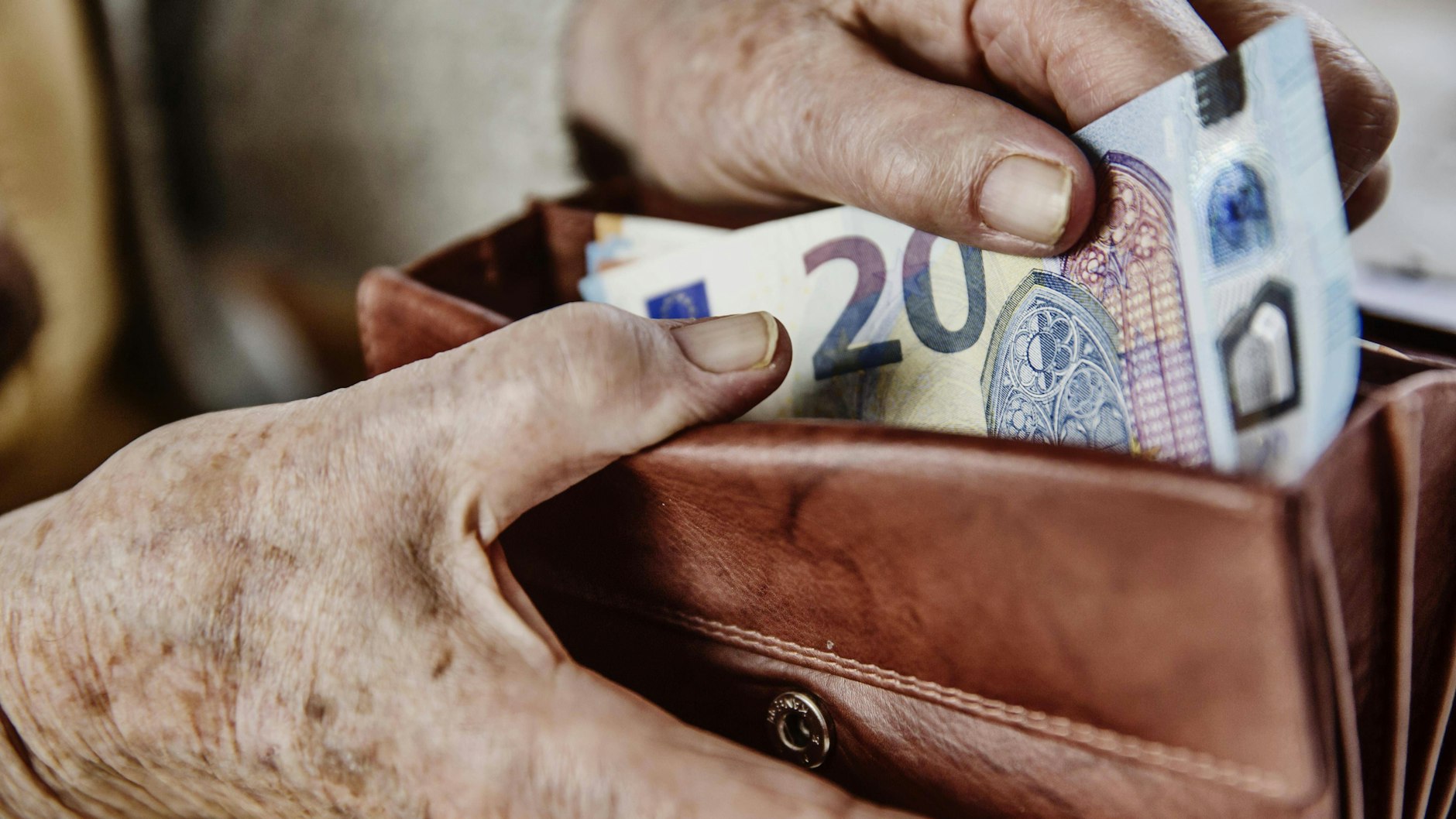 Eine Seniorin zieht einen 20 Euro Schein aus ihrem Portemonnaie.