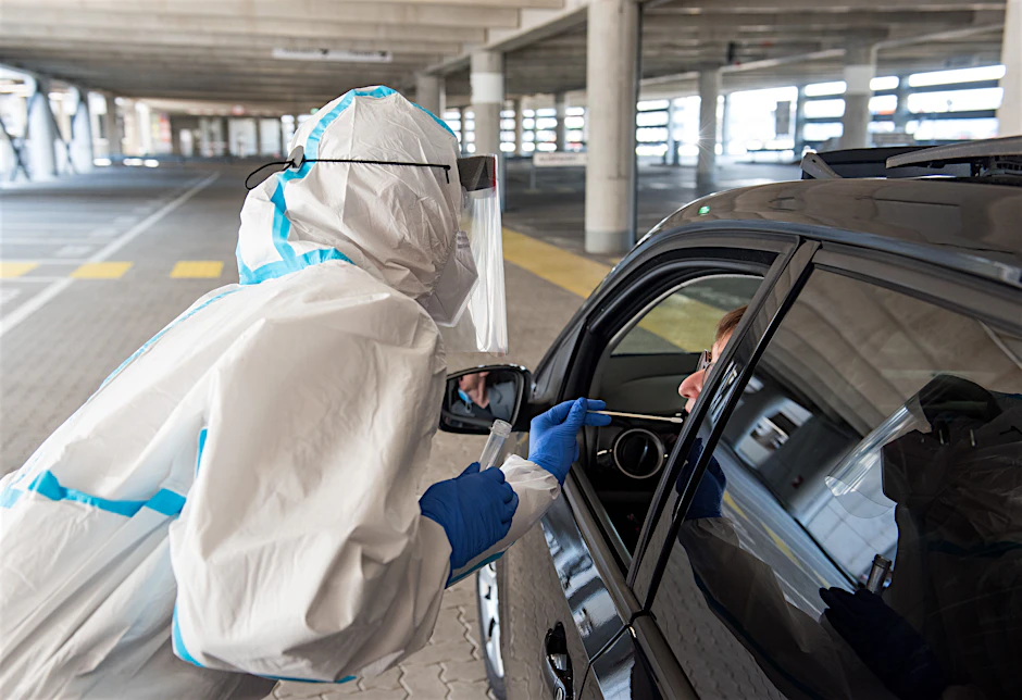 Eine Mitarbeiterin eines Drive-Through-Corona-Testzentrums nimmt einen Abstrich bei einer Autofahrerin.&nbsp;&nbsp;