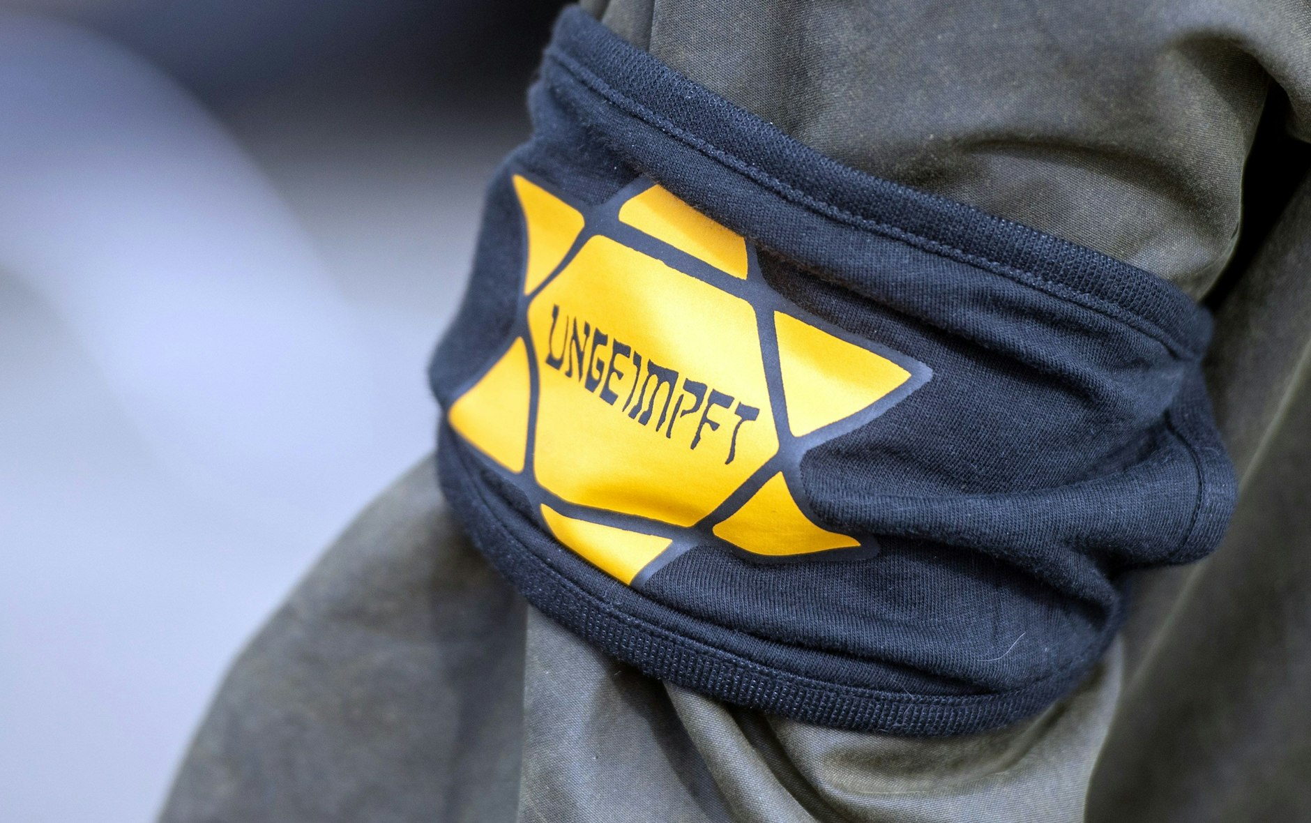 Bei einer Demonstration gegen die Einschränkungen durch die Pandemie-Maßnahmen der Bundesregierung am Brandenburger Tor trägt ein Teilnehmer eine Armbinde mit einem gelben Stern, der an einen Judenstern erinnern soll.