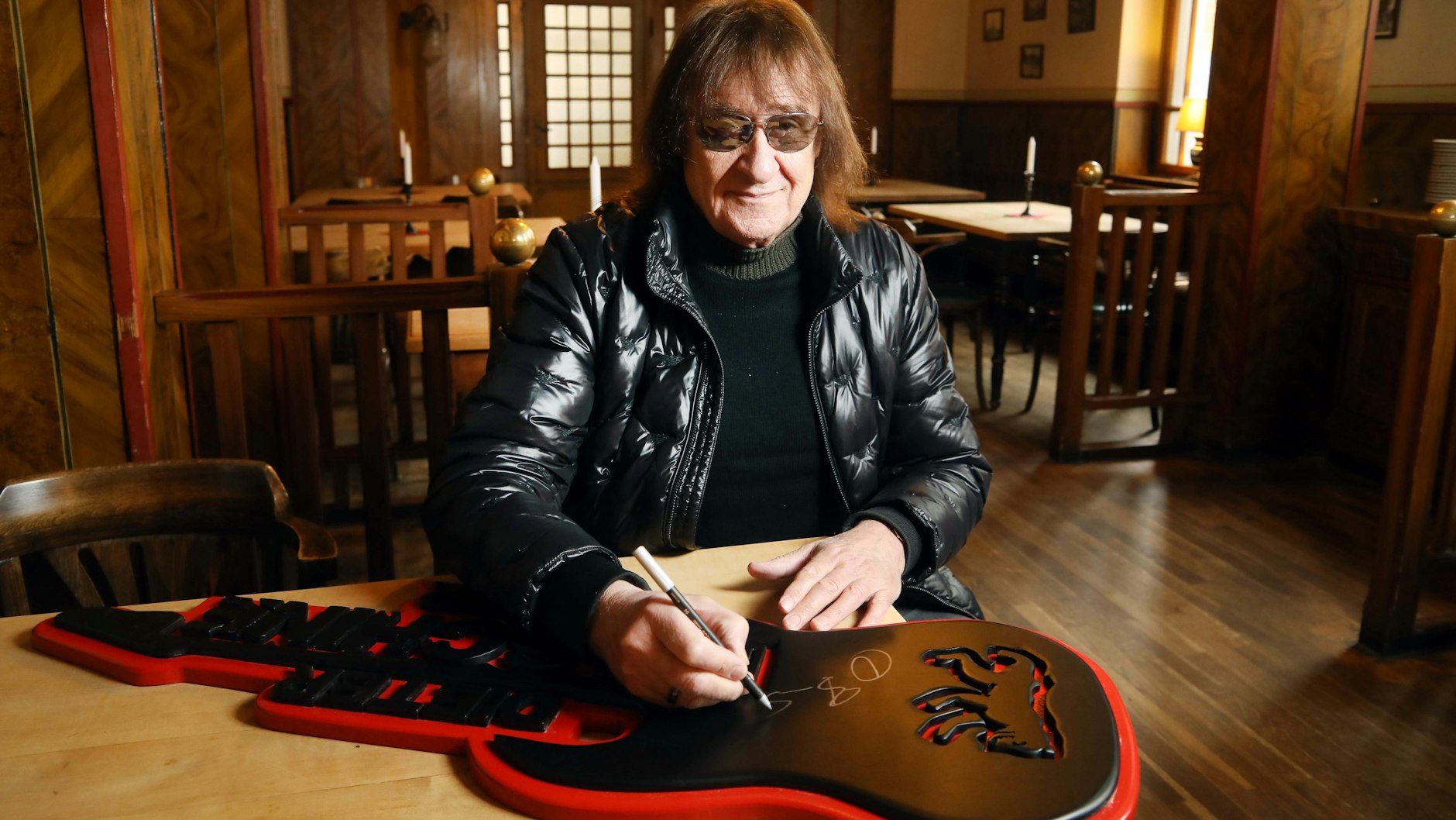 Ex-Puhdy Dieter „Maschine“ Birr signiert im Friedrichshagener „Bräustübl“ seine Kunstgitarre, mit der er dem Musiklokal helfen will.