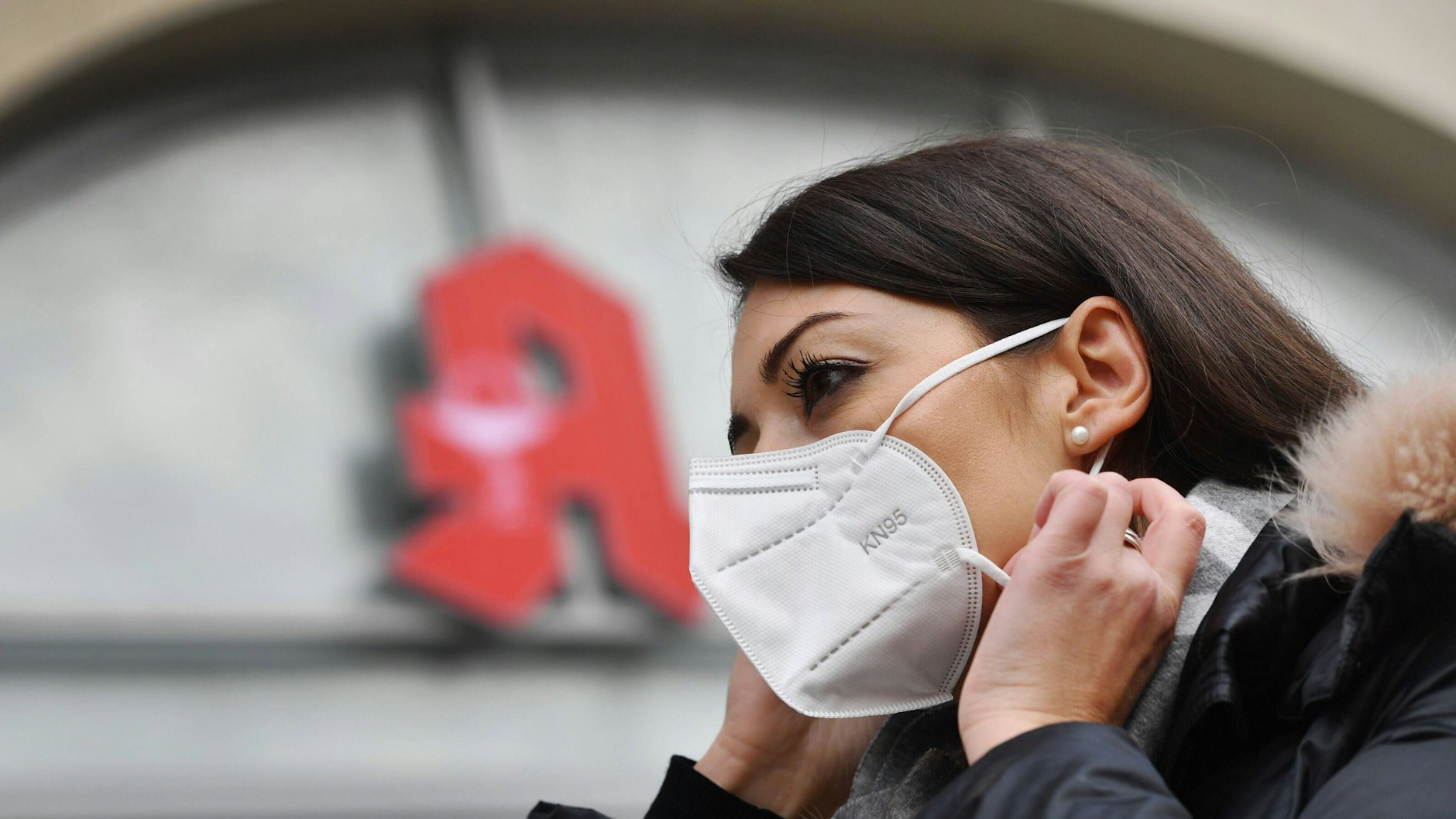 Eine Frau nestelt an ihrer FFP2-Maske herum. Mediziner sagen, dass OP-Masken im Alltag ihren Zweck besser erfüllen, weil der korrekte Umgang mit ihnen leichter ist.
