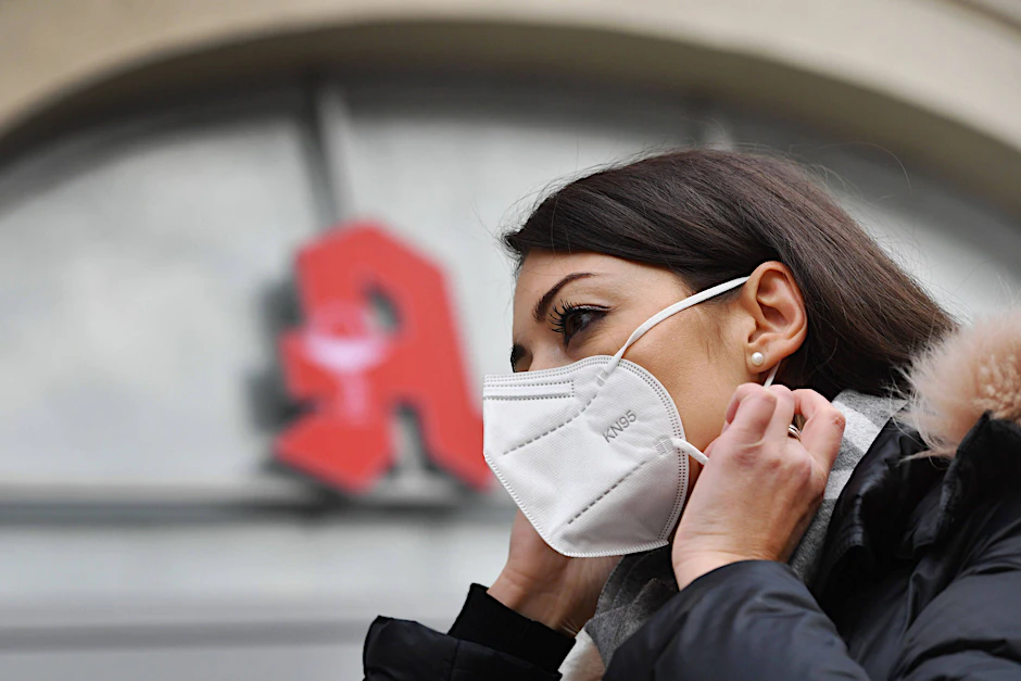 Eine Frau nestelt an ihrer FFP2-Maske herum. Mediziner sagen, dass OP-Masken im Alltag ihren Zweck besser erfüllen, weil der korrekte Umgang mit ihnen leichter ist.