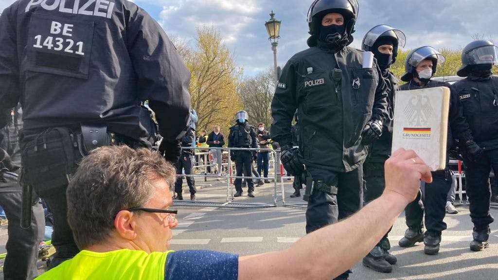 Ein Demonstrant streckt Polizisten das Grundgesetz entgegen. Tausende Menschen protestierten am Mittwoch in Berlin gegen das Infektionsschutzgesetzes. 