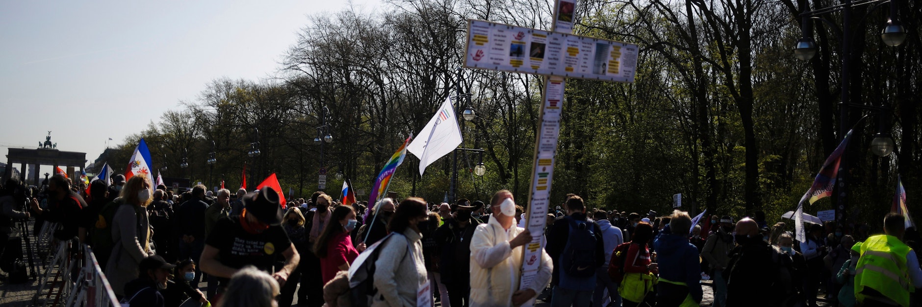 Ein Teilnehmer der Demonstration vor dem Brandenburger Tor hält ein beklebtes Kreuz in die Höhe.