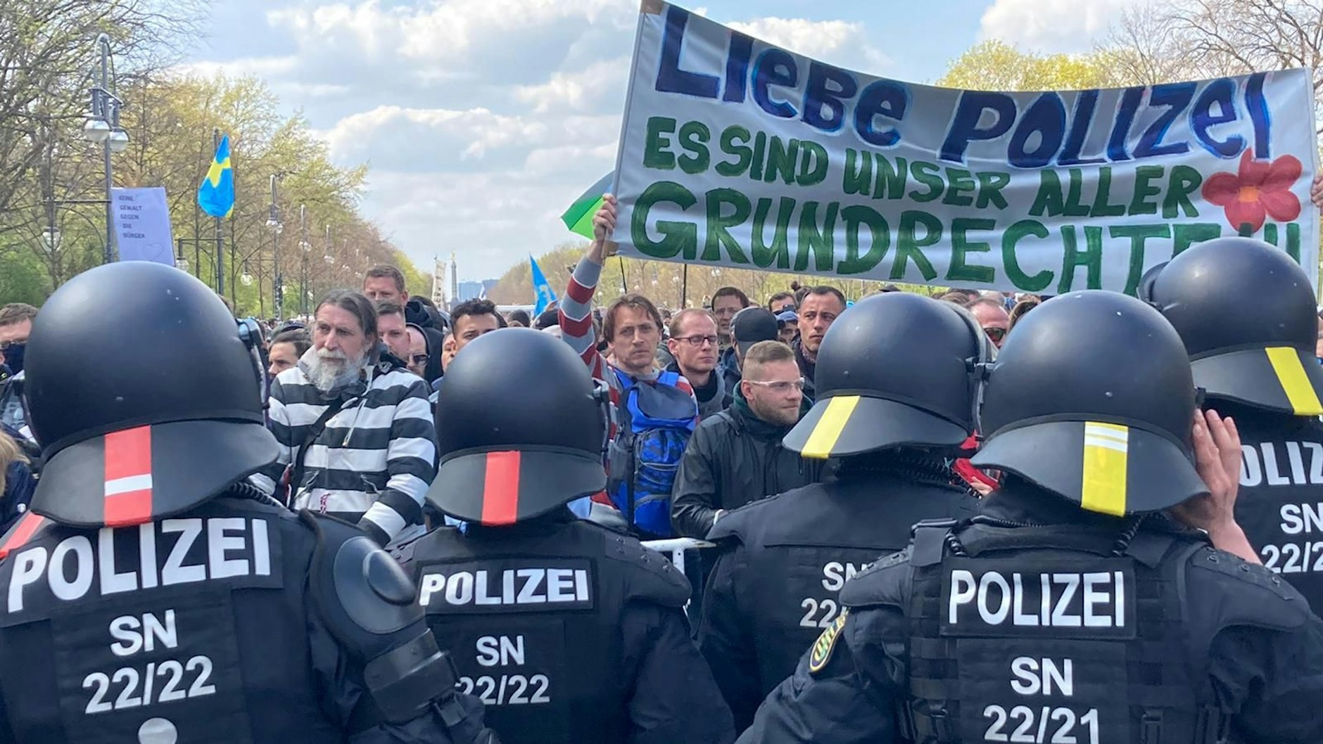 Polizisten und Demonstranten stehen sich an einer Absperrung gegenüber. 