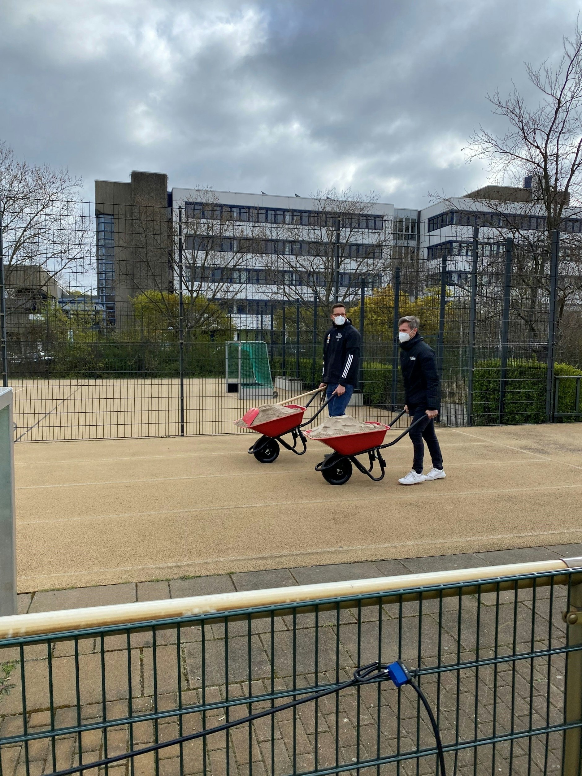 Musste am Ende selber Hand anlegen: Michael Parensen und Roland Hoffer schieben die Schubkarren mit dem Sand des symbolischen Spatenstiches wieder runter vom Platz. 