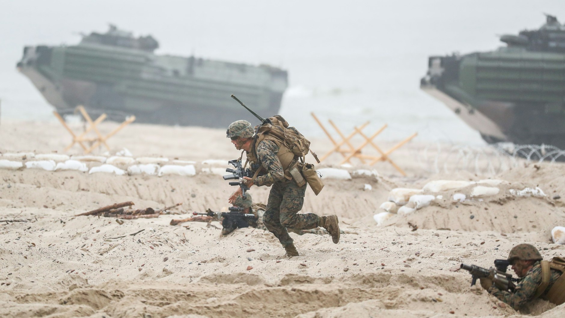 US-amerikanische Nato-Soldaten laufen in Ustka in Polen bei einem Marinemanöver über einen Strandabschnitt vor Amphibienpanzern.
