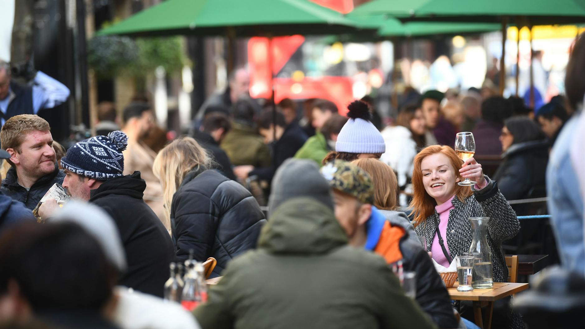 Eine Frau hebt ein Glas im Außenbereich eines Pubs in London.