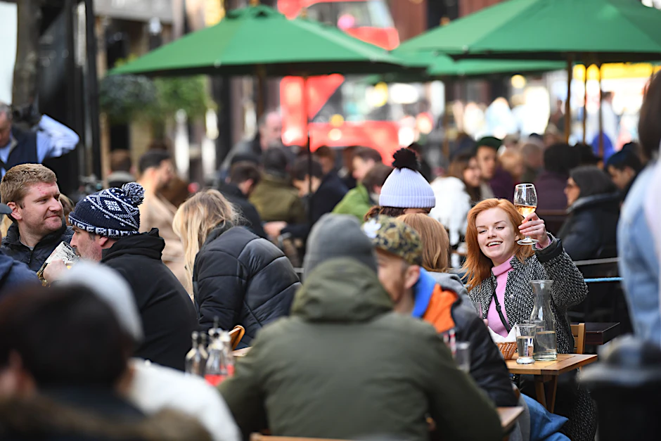 Eine Frau hebt ein Glas im Außenbereich eines Pubs in London.