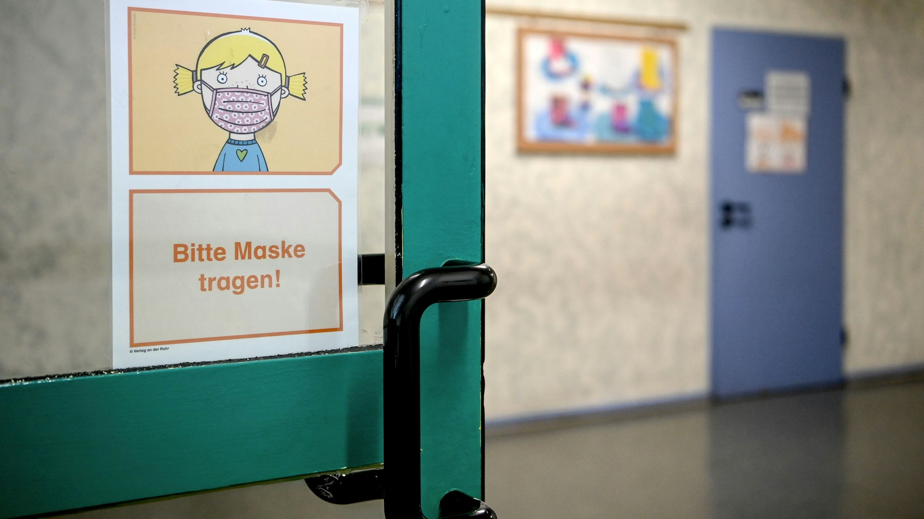 Ein Schild mir der Aufschrift „Bitte Maske tragen!“ hängt auf einem Flur der Grundschule in der Köllnischen Heide.