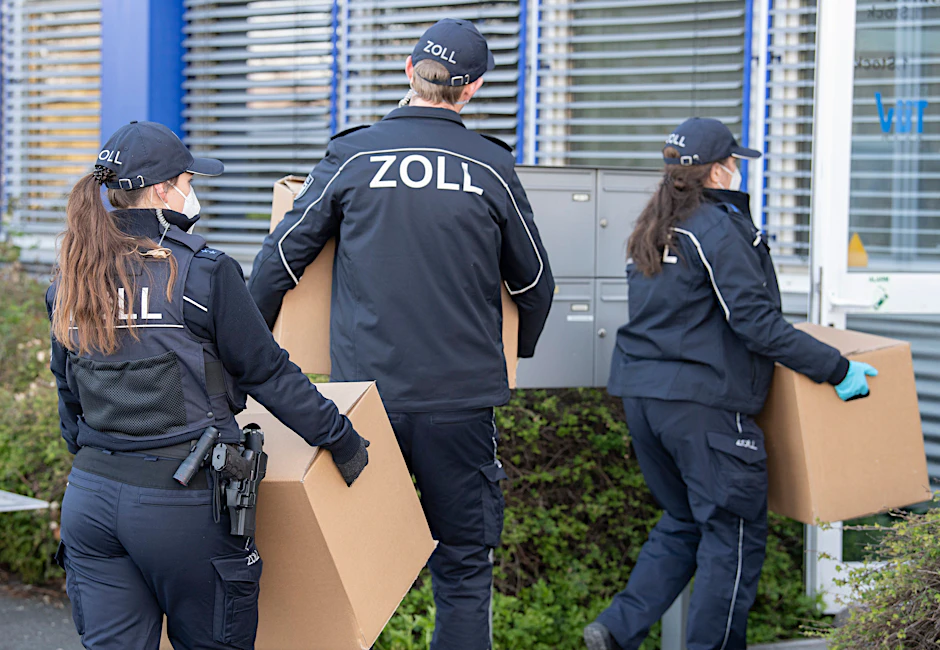 Zollbeamte tragen während einer Razzia leere Kartons für die sichergestellten Beweismitteln ins Gebäude.&nbsp;