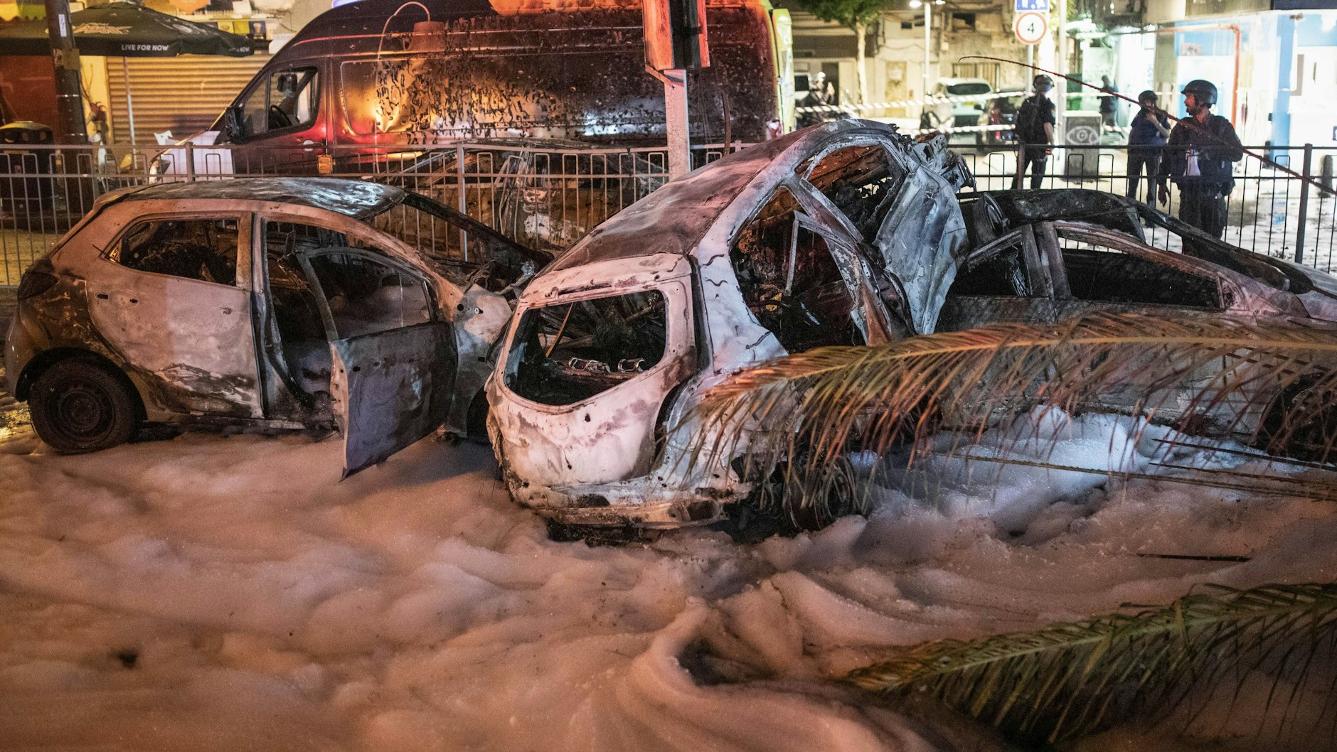 Schäden in der israelischen Stadt Holon: Mehrere verbrannte Fahrzeuge sind mit Löschschaum bedeckt. Die Fahrzeuge wurden von einer Rakete getroffen, die aus dem Gazastreifen in Richtung Israel abgefeuert wurde.
