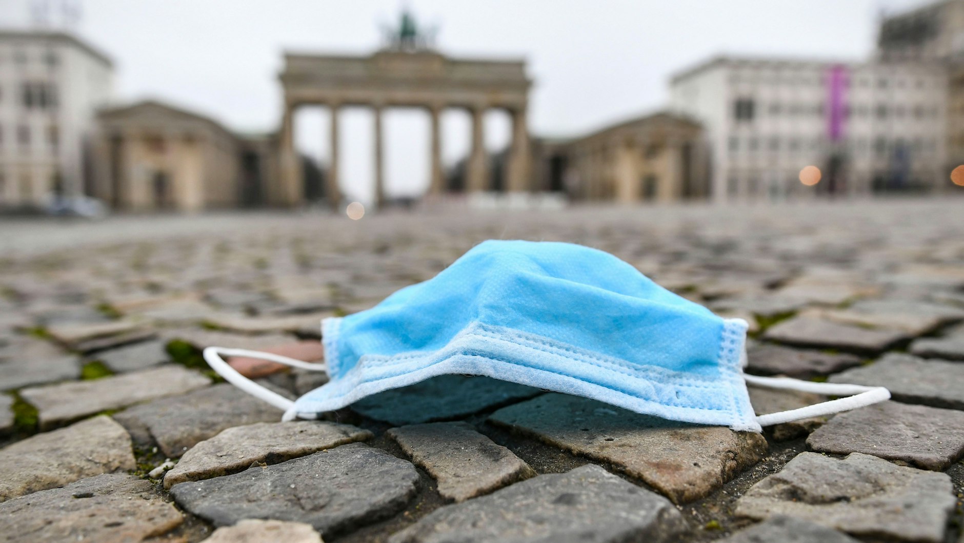 Eine weggeworfene Corona-Maske liegt am Brandenburger Tor in Berlin.