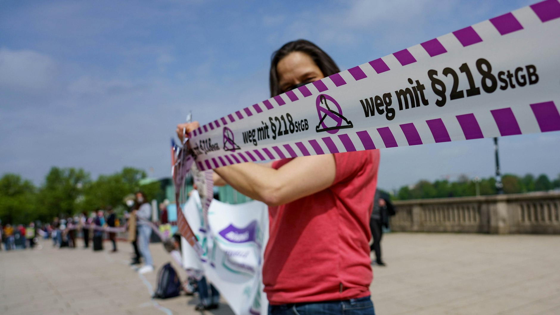 Menschen mit einem Flatterband mit der Aufschrift „weg mit §218“ stehen auf dem Hamburger Jungfernstieg.
