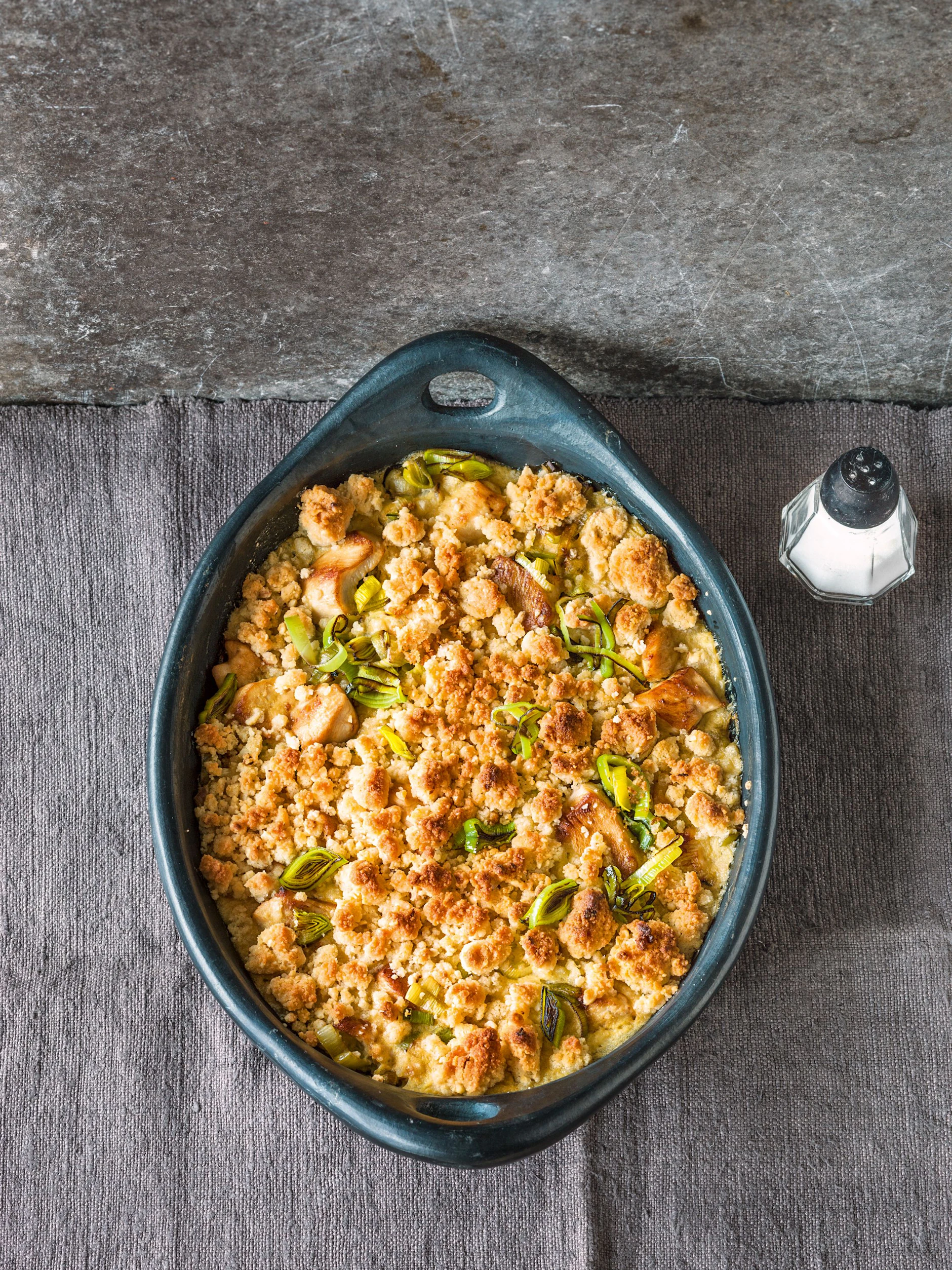 Die Kruste für den  Hähnchen-Lauch-Auflauf ist mit Streuseln überbacken, die aus Mehl, Semmelbrösel, Butter, gehackten Haselnusskernen und Parmesan zubereitet werden.