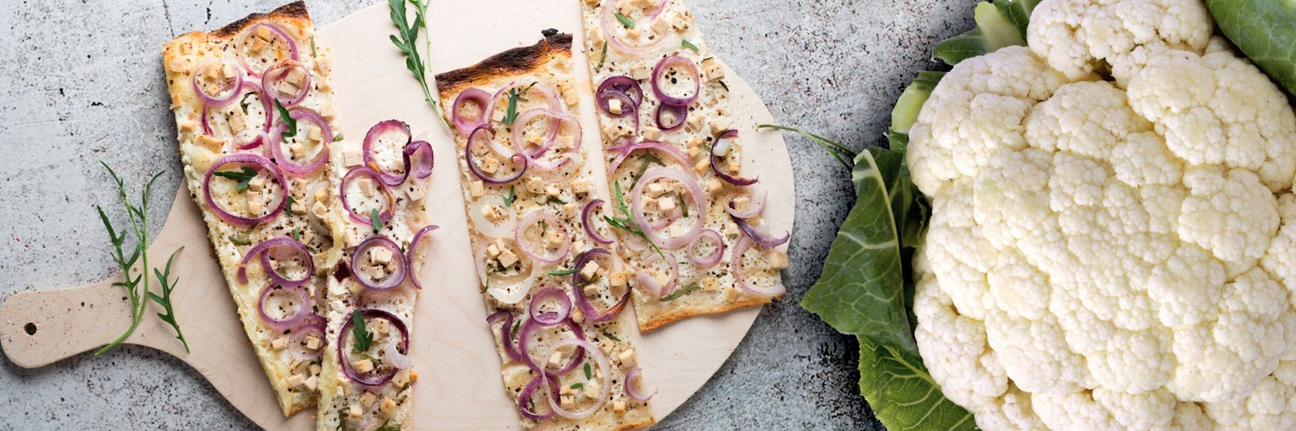 Wer beim Flammkuchen den Boden durch einen Teig aus Blumenkohl ersetzt, spart Kohlenhydrate.