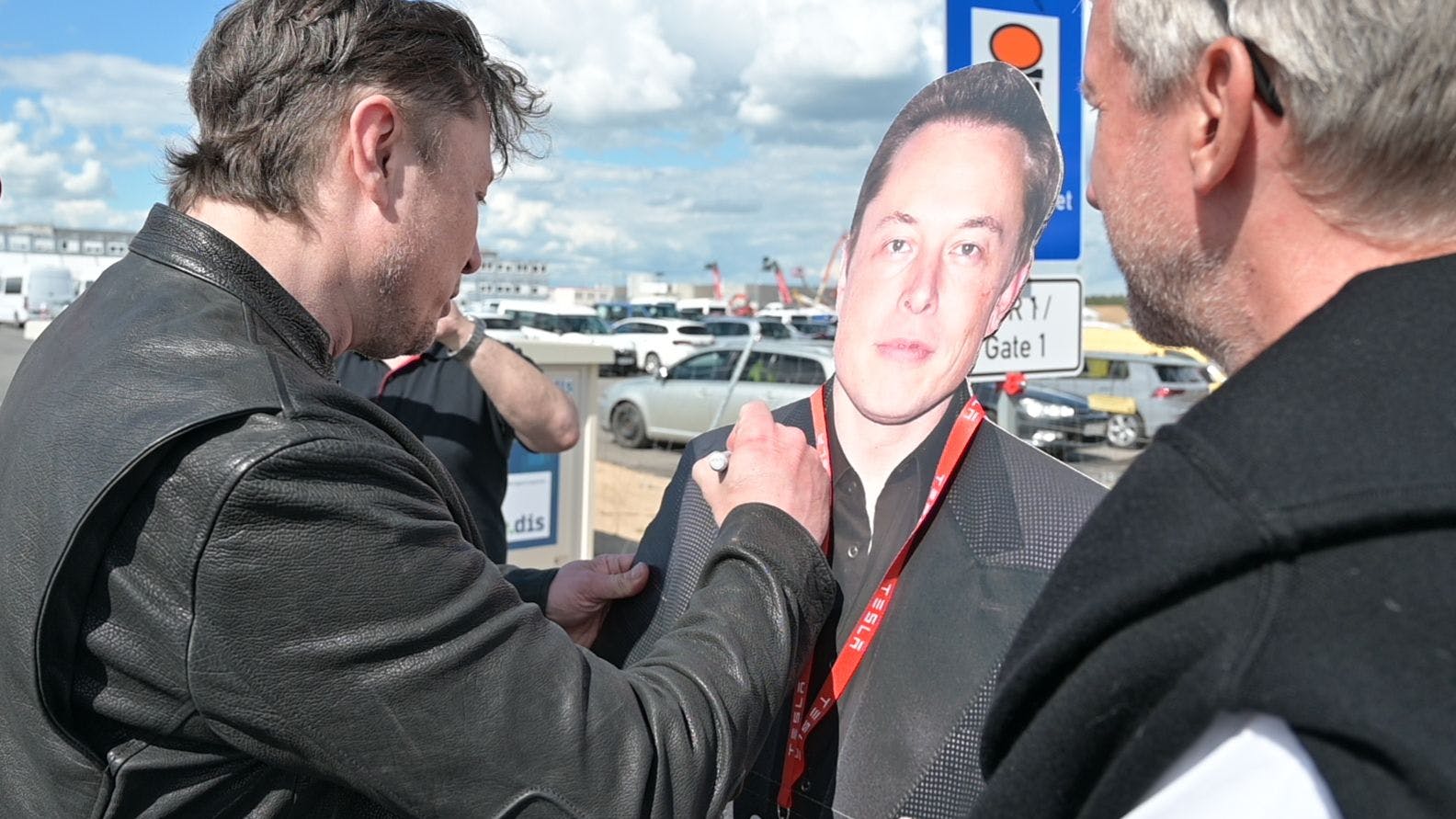 Elon Musk signiert den Pappaufsteller eines Tesla-Fans. 
