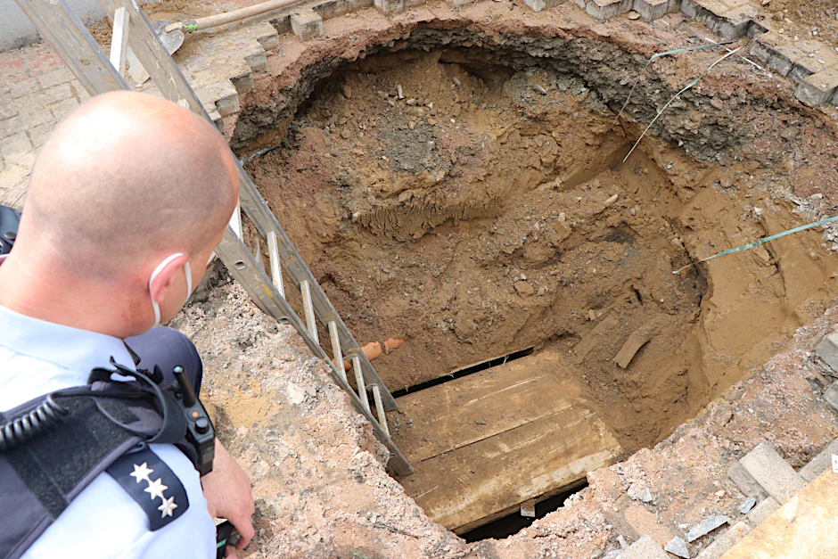 Ein Polizist schaut auf das Loch eines Tunnels, den Unbekannte zur Volksbank gegraben haben.&nbsp;