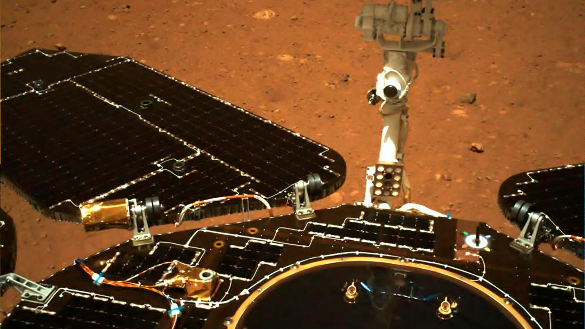 Auf diesem Foto, das von Chinas Mars-Rover „Zhurong“ aufgenommen wurde, sind die Solarpaneele und die Antenne des Rovers ausgefahren, während der Rover auf seinem Lander auf der Marsoberfläche sitzt.