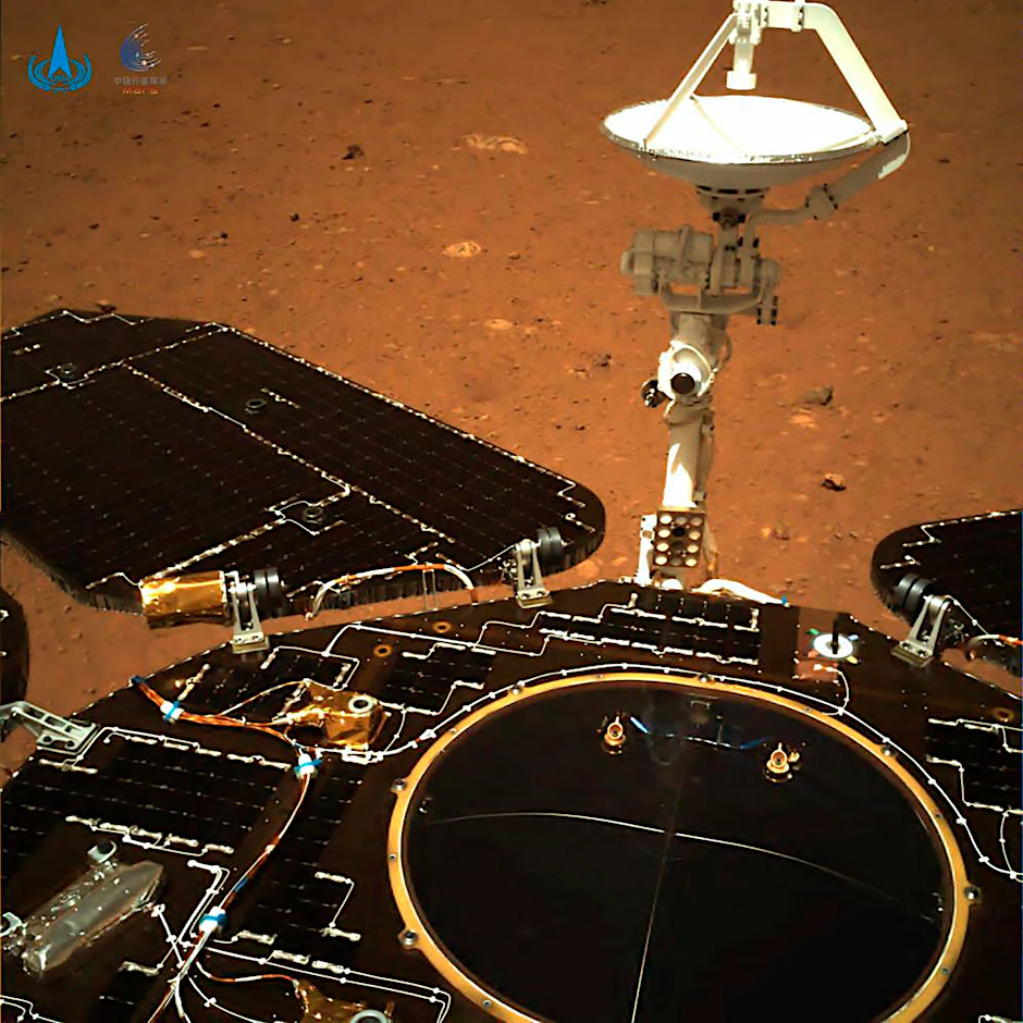 Auf diesem Foto, das von Chinas Mars-Rover „Zhurong“ aufgenommen wurde, sind die Solarpaneele und die Antenne des Rovers ausgefahren, während der Rover auf seinem Lander auf der Marsoberfläche sitzt.
