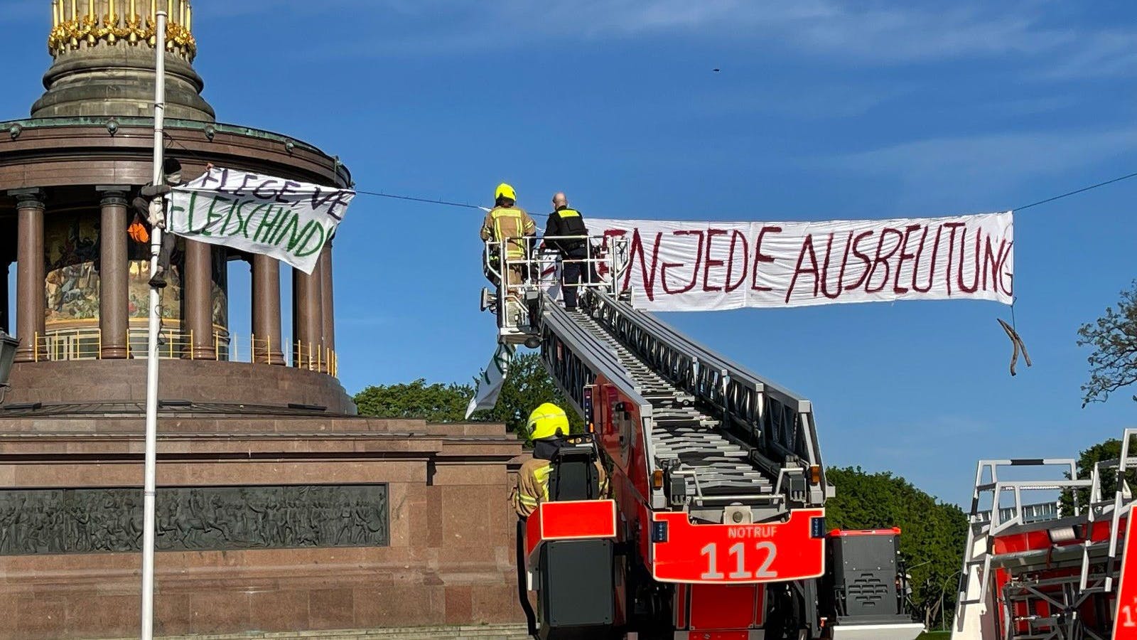 Feuerwehrleute entfernten mit einer Drehleiter die Transparente vor der Siegessäule am Großen Stern.