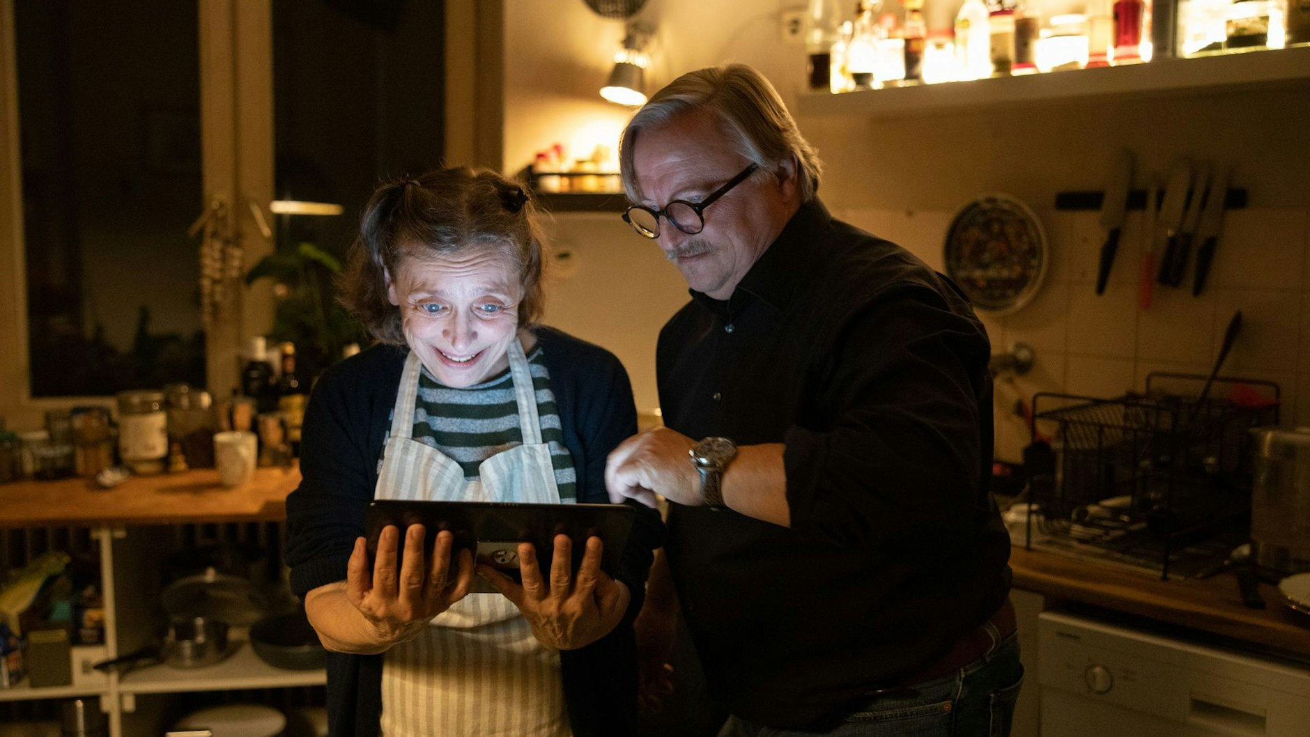 Ralph Friesner (Axel Prahl, r.) überrascht seine Mitbewohnerin Karin (Katharina Thalbach, l.) mit einem Tablet. Endlich kann sie mit ihrem Enkel sprechen.