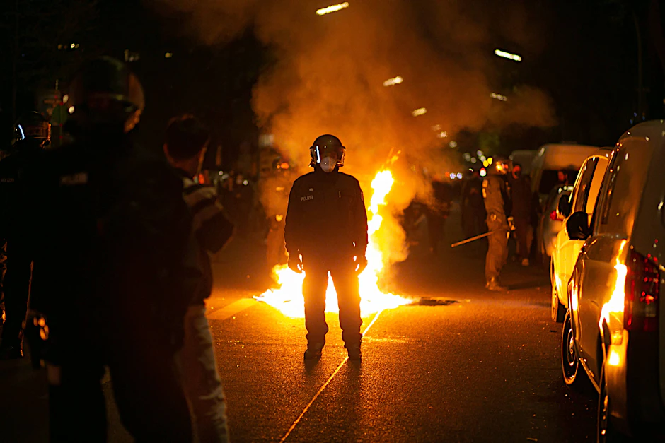 Ein Polizist steht am 1. Mai in Berlin-Neukölln vor einer brennenden Barrikade.