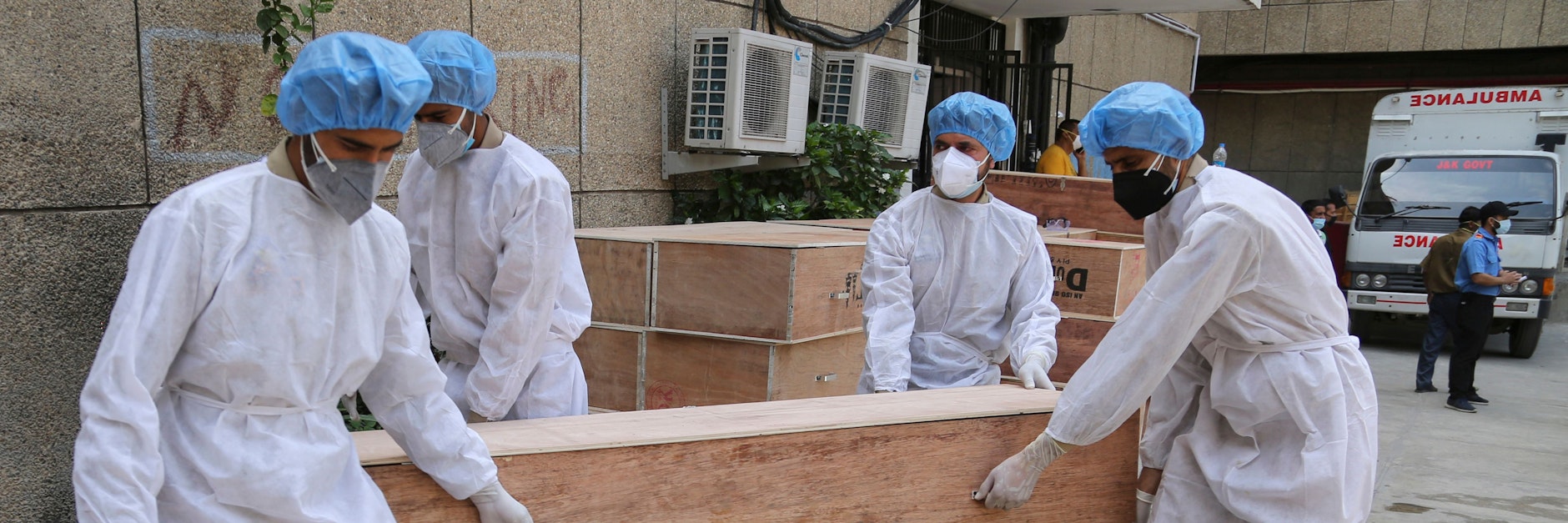 Soldaten des State Disaster Response Fund (SDRF) in Jammu und Kashmir in Schutzausrüstung tragen leere Särge für den Transport von Corona-Toten.