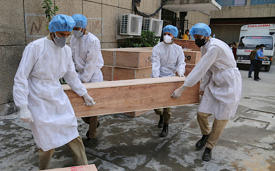 Soldaten des State Disaster Response Fund (SDRF) in Jammu und Kashmir in Schutzausrüstung tragen leere Särge für den Transport von Corona-Toten.